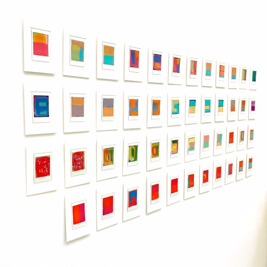oil on instax abstracts by Sarah Kudirka, artist, mounted in four line grid on white wall